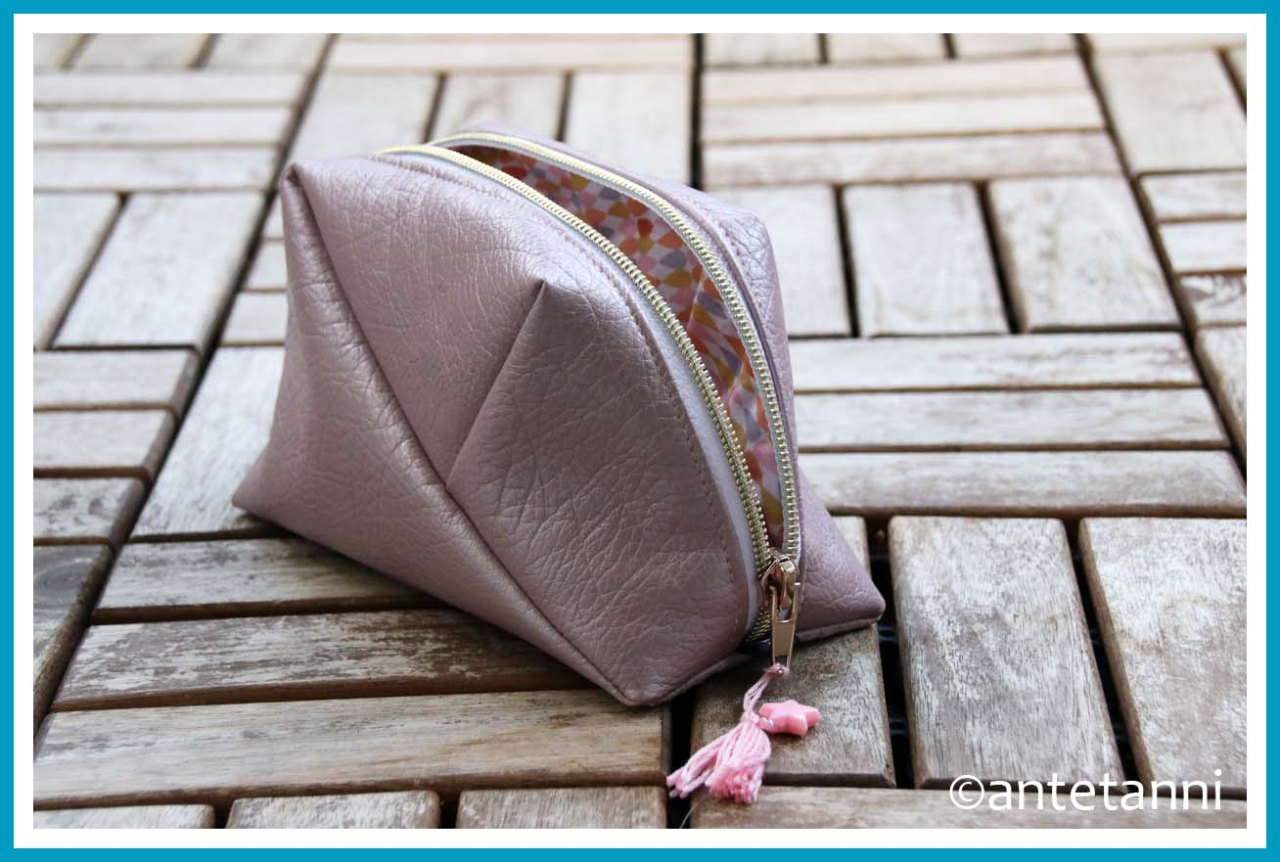 Geo-Bag mit geöffnetem Reißverschluss mit Blick auf beschichte Baumwolle als Innenfutter. Am goldfarbenen Reißverschluss hängen eine rosafarbene Tassel und ein Stern.