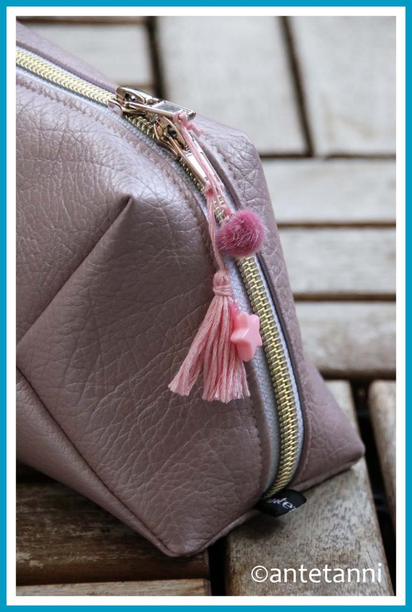 Geschlossene Geo-Bag in Seitenansicht mit Reißverschluss mit goldener Raupe und Zierlementen - Tassel aus Stickgarn, Stern-Perle und Pompon