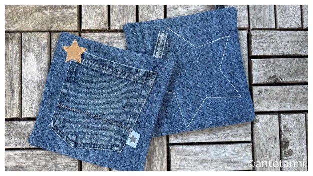 Zwei Jeans-Topflappen auf Holz. Die Vorderseite zeigt eine aufgesetzte Hosentasche und einen Stern aus Snappap in Hellbraun, die Rueckseite einen mit hellem Garn aufgesteppten großen Stern.